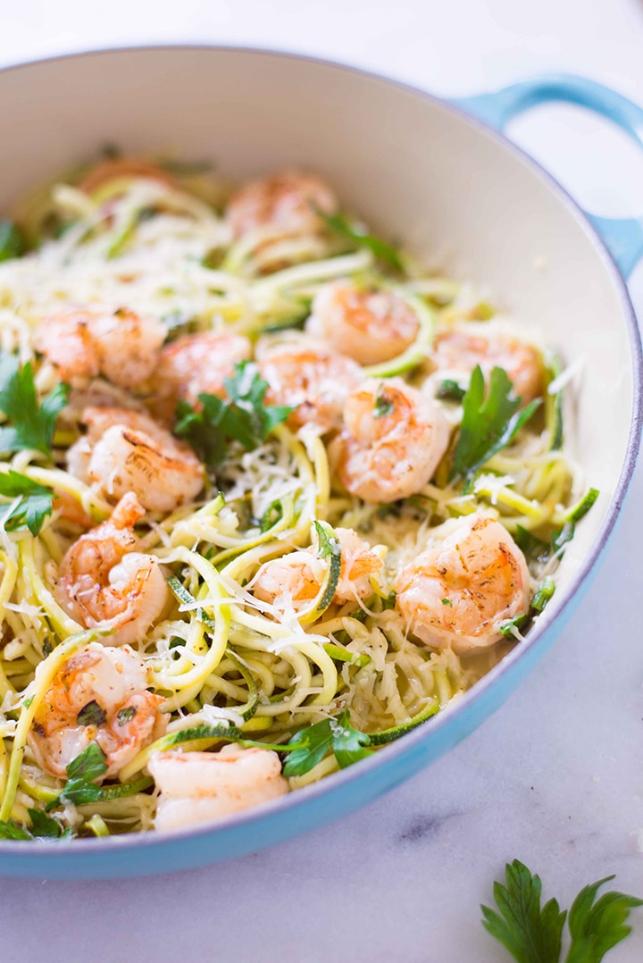 Side view of the 15 minute healthy shrimp scampi on a bed of zucchini noodles, garnished with fresh parsley and is ready to eat.