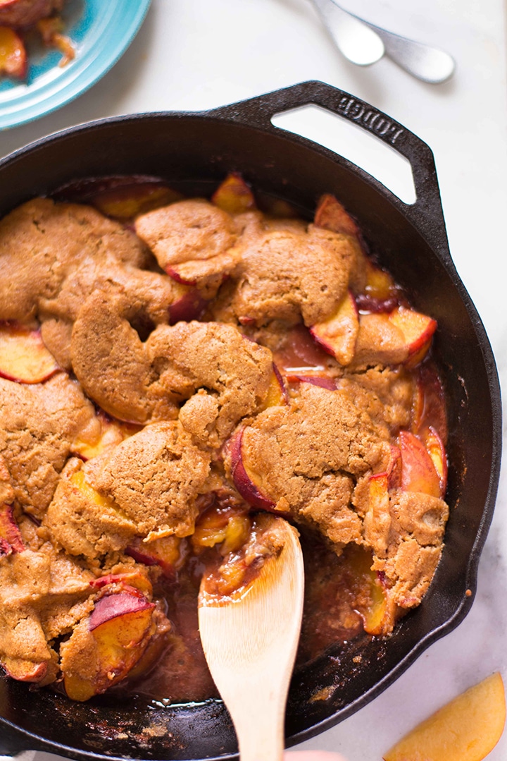 Overhead image of cast iron skillet filled with fresh peach cobbler that has been baked and is ready to serve.