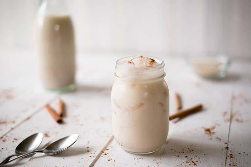 Horchata drink, placed together with serving spoons and whole cinnamon sticks 