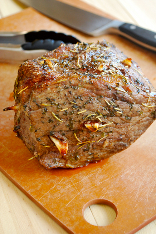Image of the cooked roast beef that has been removed from the oven and is ready to slice, sitting on a cutting board, resting.