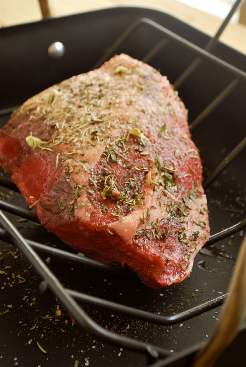 Image of the roast beef that has been seasoned with sea salt, pepper, garlic, rosemary, tarragon, thyme, and other spices and is ready to go into the oven in the roasting rack.