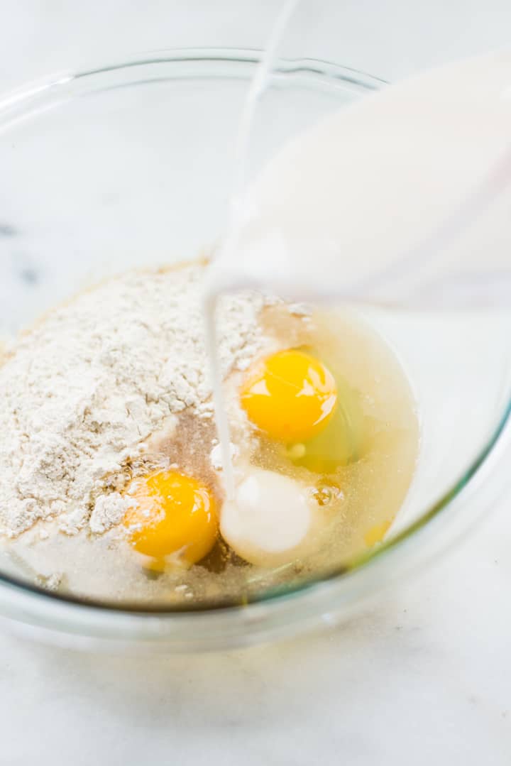Image of a glass bowl with eggs and almond milk being added to the dry ingredients for Homemade Healthy Crepes.