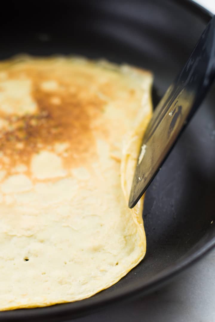 Closeup image of a Homemade Healthy Crepe being flipped in a skillet as it is cooking.