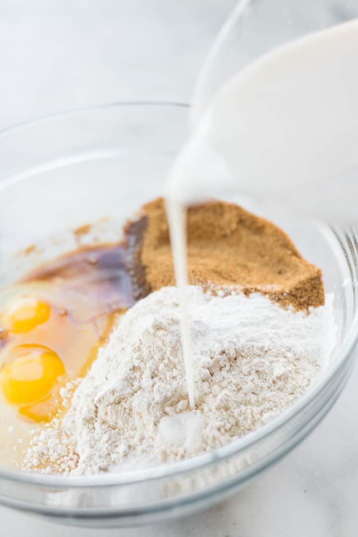 Overhead view of the bowl of ingredients, with almond milk being poured into the mix.