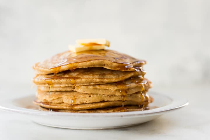 Close up side view of a stack of Healthy Diner Style Pancakes, topped with pure maple syrup and butter, ready to be eaten.