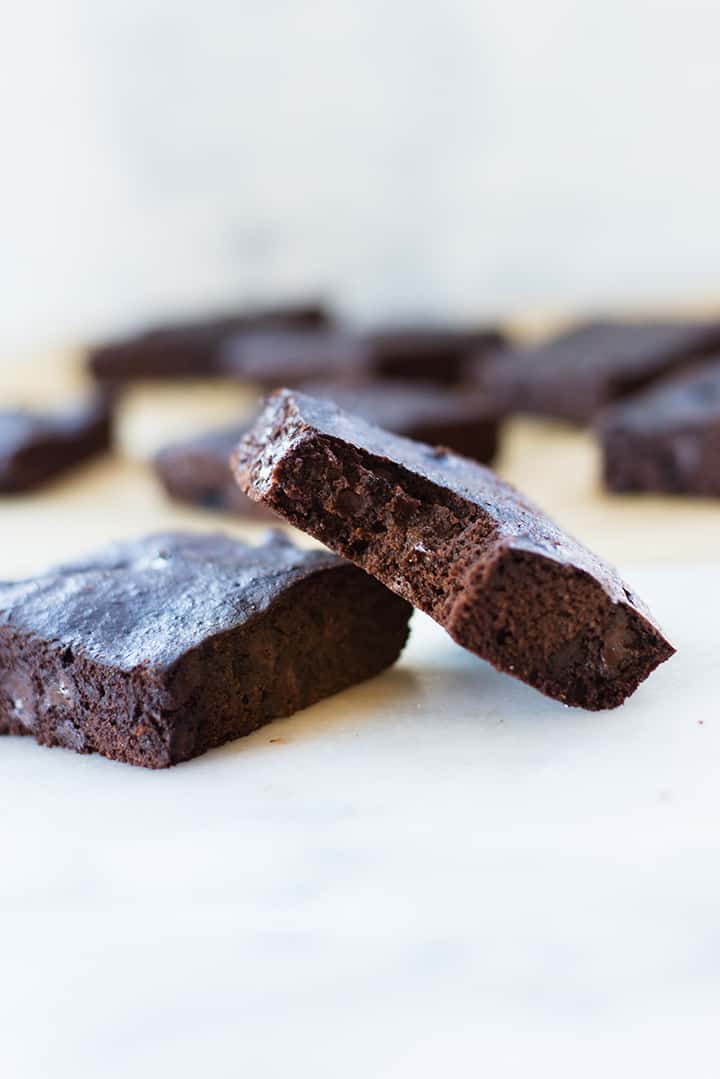 Side view of cut up Healthy Dark Chocolate Brownies, two stacked up against each other and several brownies in the background.