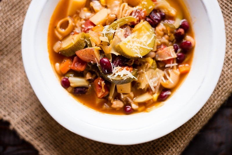 Close up overhead view of a bowl of Healthy Minestrone Soup, garnished with parmesan.