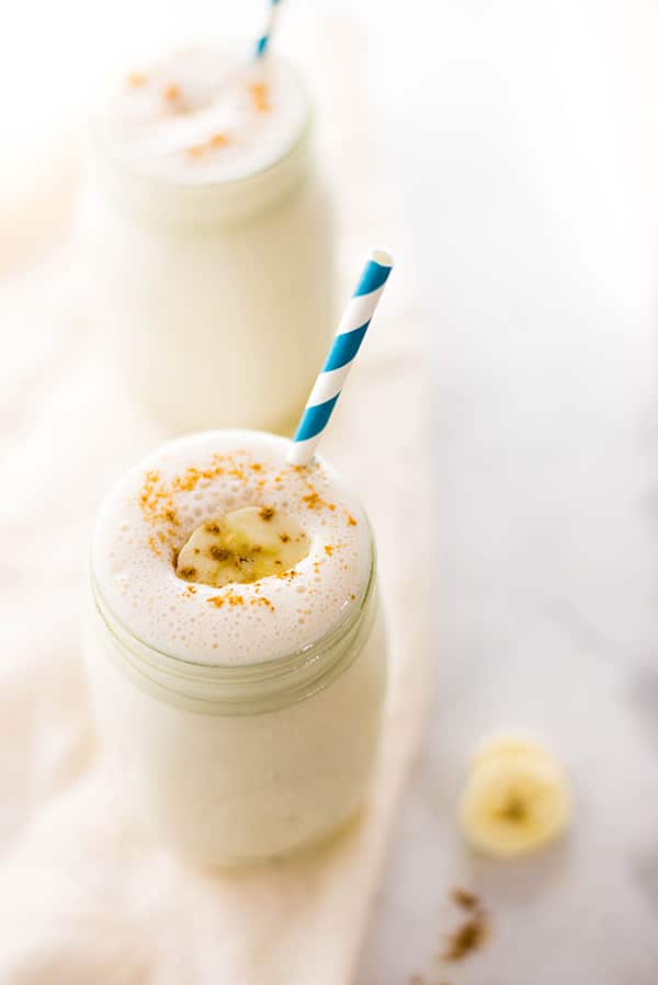 A banana protein shake, topped with sliced banana, dusted with cinnamon and poured in a Mason jar 