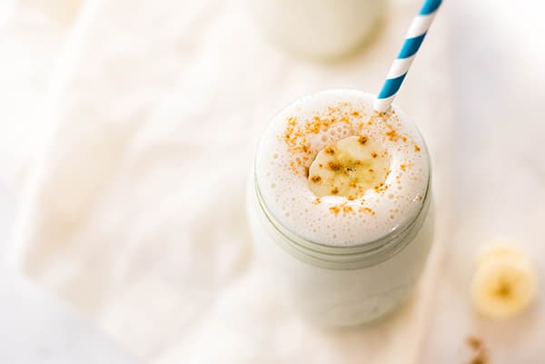 High angle photo of a banana protein shake, served in a Mason jar and ready to be consumed 