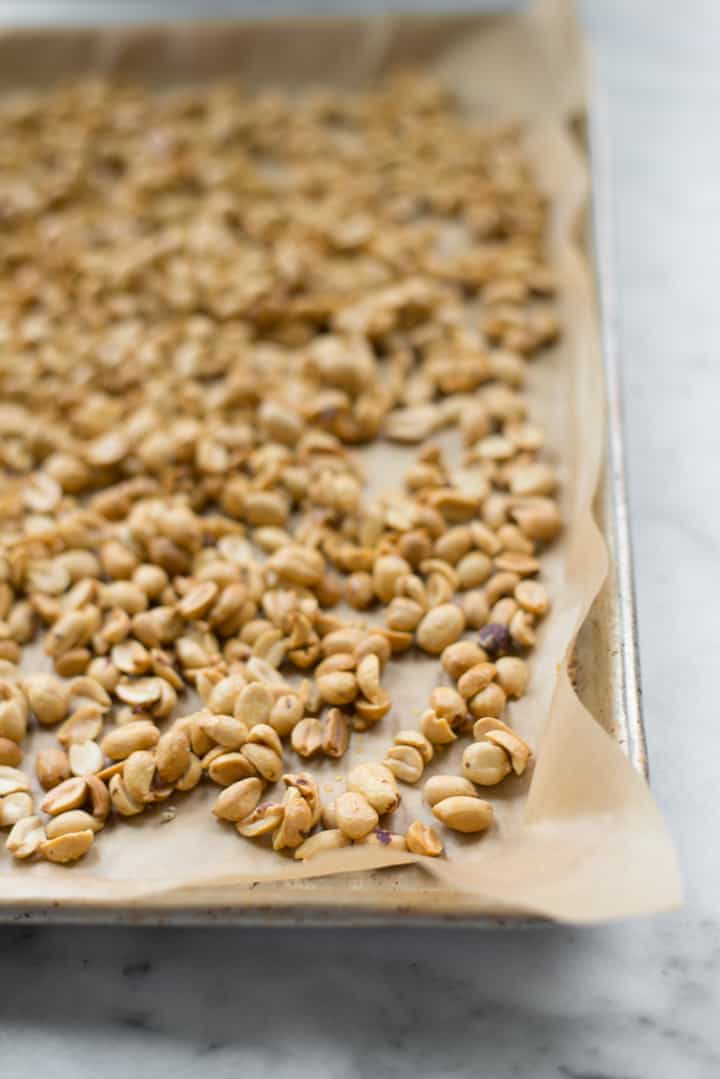 Overhead image of raw honey and salt covered roasted peanuts, ready to be put in the oven as preparation for Honey Roasted Peanut Butter.