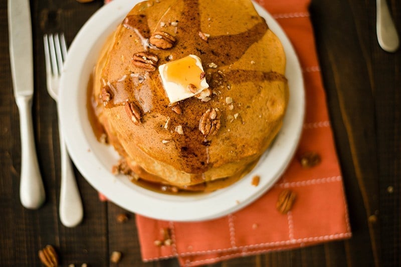 Overhead view of Healthy Pumpkin Pancakes, served with butter and maple syrup on a white plate
