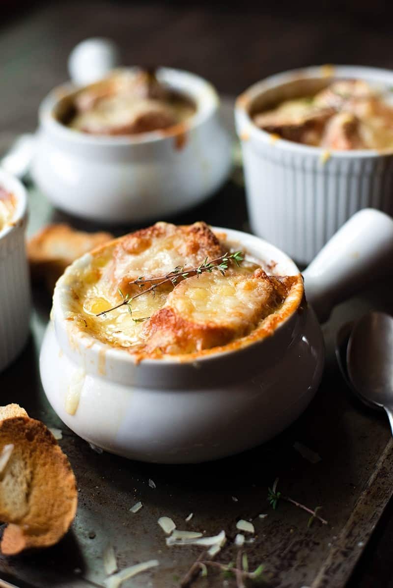 French Onion Soup in 4 bowls, with browned baguette and cheese, fresh out of the oven.