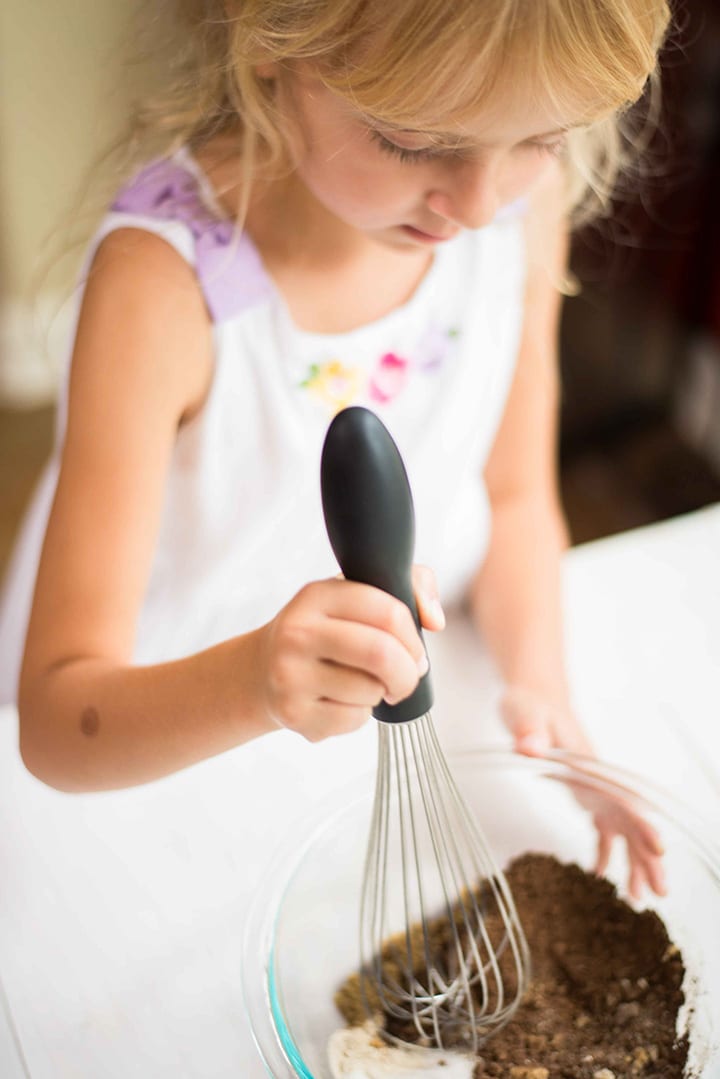 Girl stirring the hot chocolate mix which contains dark cocoa powder, coconut sugar, cinnamon, and vanilla powder to show how to make hot chocolate mix.