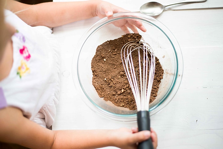 Young girl with a mixing bowl that has the best hot chocolate mix recipe and is ready to be turned into hot chocolate.