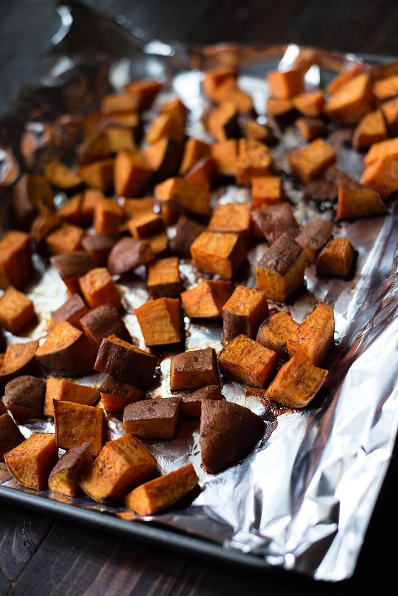 Close up view of a foil-lined sheet pan with baked Healthy Roasted Sweet Potatoes With Coconut Oil
