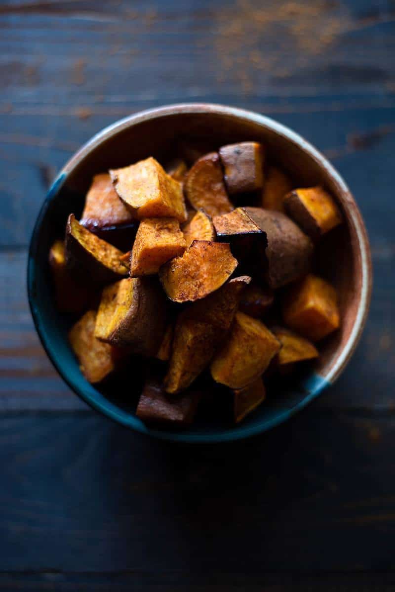 Close up overhead image of an earthenware bowl filled with Healthy Roasted Sweet Potatoes With Coconut Oil.
