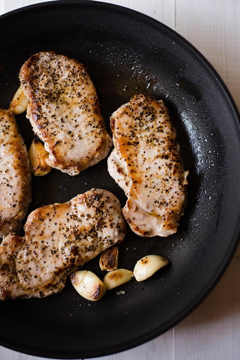 Garlic roasted pork chops pan roasting in a skillet—a healthy way to cook pork chops 