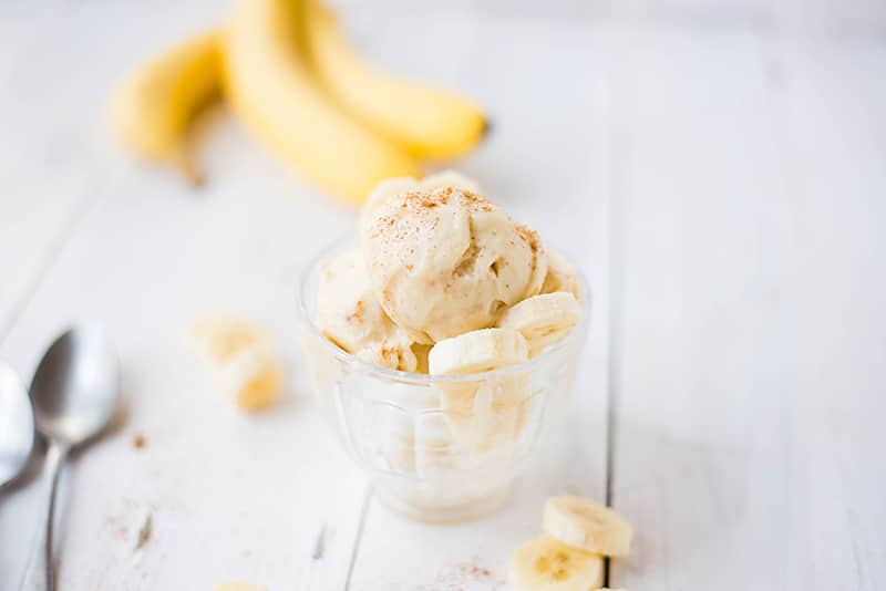 Serving of banana ice cream garnished with fresh banana slices and ground cinnamon, ready to be served and enjoyed 
