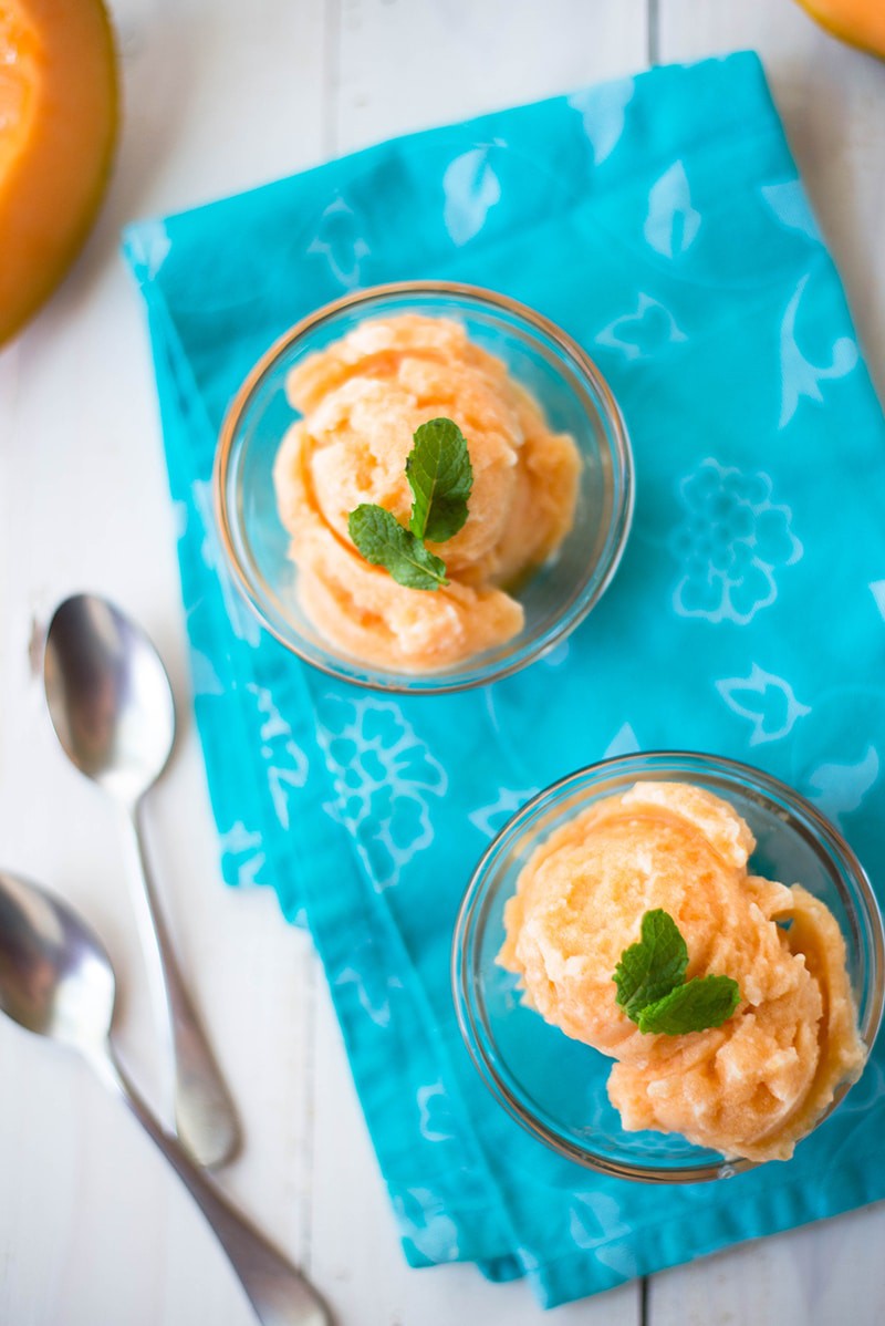 Close up of cantaloupe sorbet garnished with fresh mint leaves and served in glass bowls 