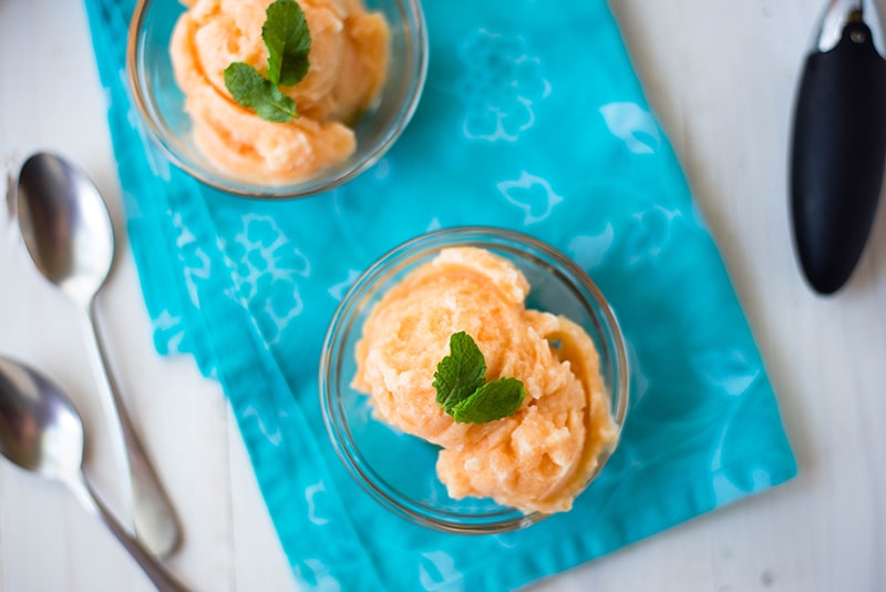 Homemade cantaloupe sorbet garnished with fresh mint leaves and served in glass bowls