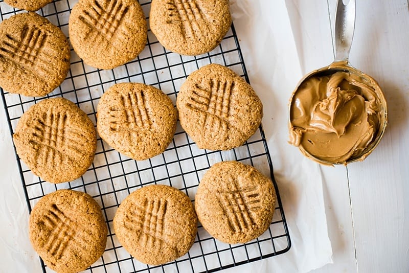 Overhead view of the baked peanut butter protein cookies, setting next to a cup of peanut butter.