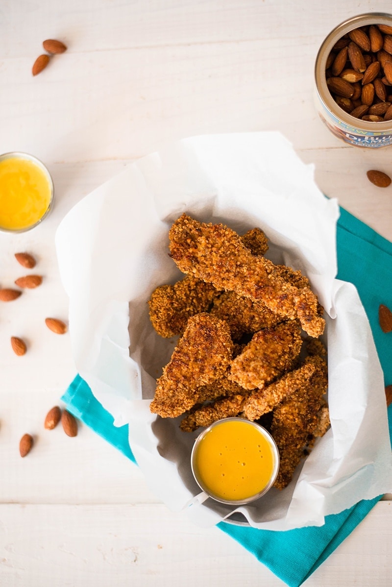 Baked almond chicken strips pictured with honey mustard dipping sauce, ready to be served and enjoyed
