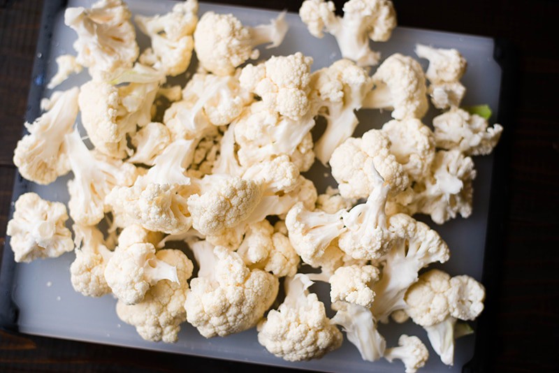 Raw chopped cauliflower florets on a chopping board, to be roasted and used for cauliflower gratin dish