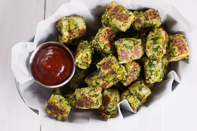 Close up image of the baked broccoli tots which are ready to be dipped into the healthy ketchup and enjoyed as a kid friendly vegetarian side or snack.