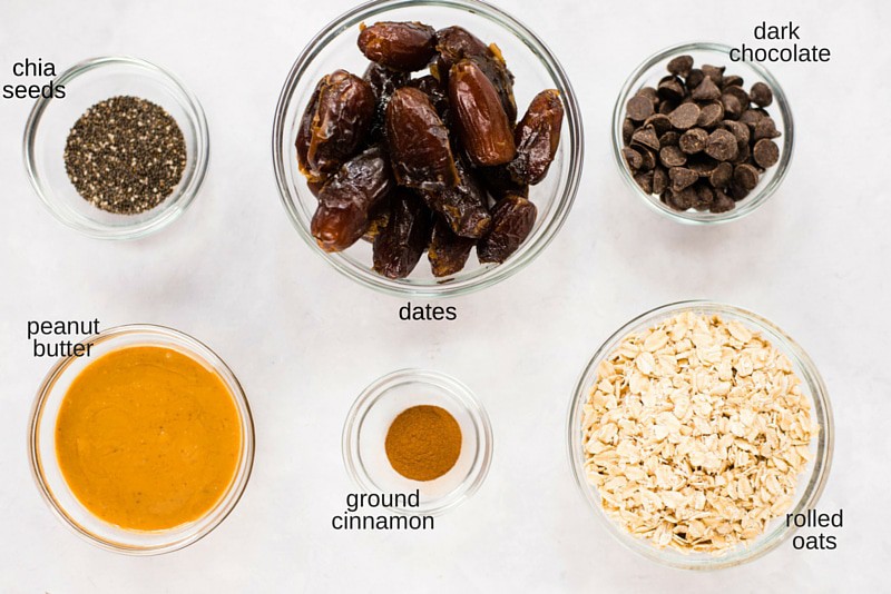 Overhead image of the ingredients for No Bake Chocolate Peanut Butter Energy Balls, including cinnamon, peanut butter, dates, chia seeds, dark chocolate and oartmeal.