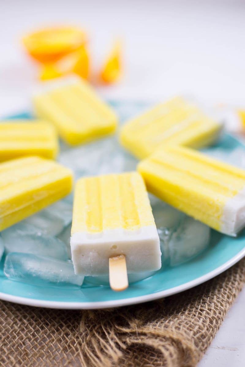 Side angle photo of 3-ingredient orange creamsicles placed over a deep plate bowl filled with ice cubes 