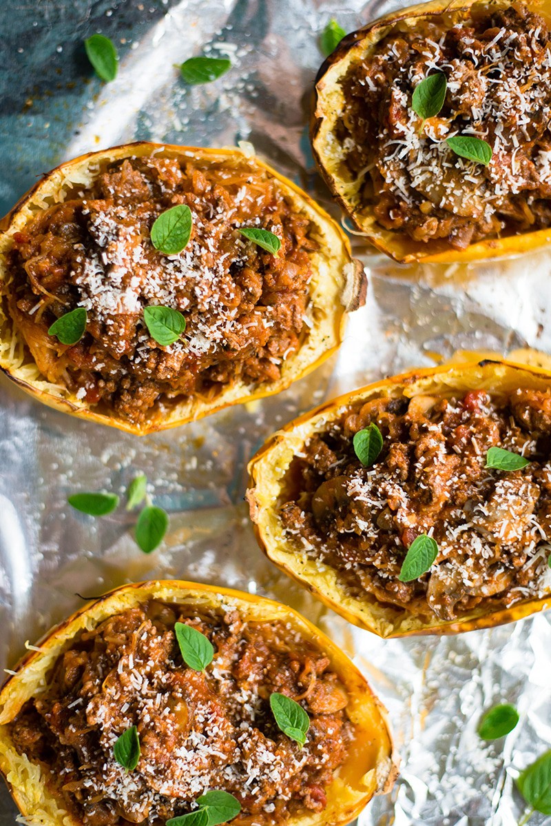 Baked spaghetti squash bowls filled with marinara sauce and garnished with fresh basil leaves and Parmesan cheese 