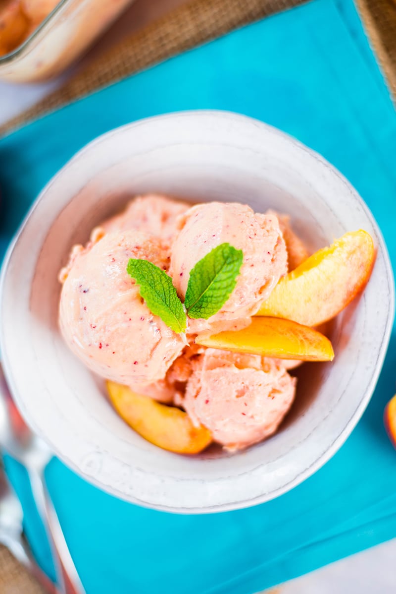 Close up of a serving of peach frozen yogurt, garnished with fresh peaches and mint leaves 