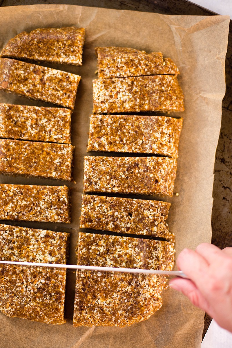 Overhead image of Apricot, Almond & Flaxseed Homemade Energy Bars being sliced on a parchment paper covered sheet pan; they are a good way to use flaxseed meal.
