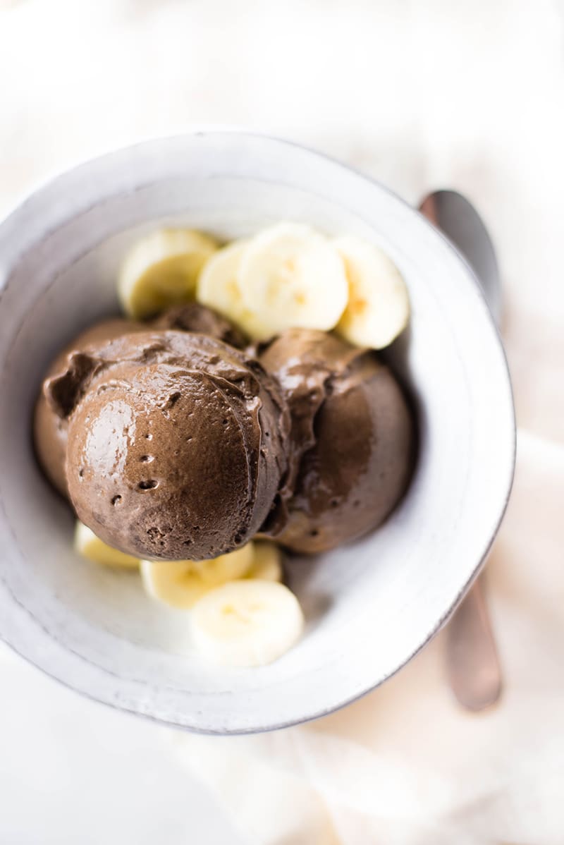 Close up of chocolate banana ice cream, served in a bowl together with fresh banana slices 