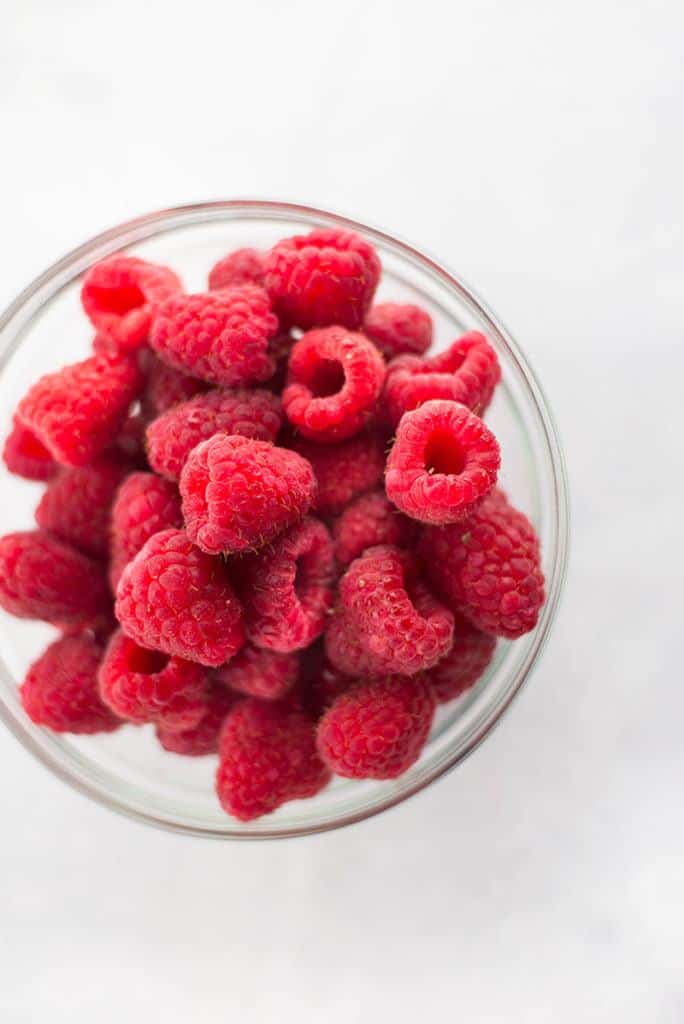 Overhead view of a glass bowl full of raspberries, an anti-inflammatory food.
