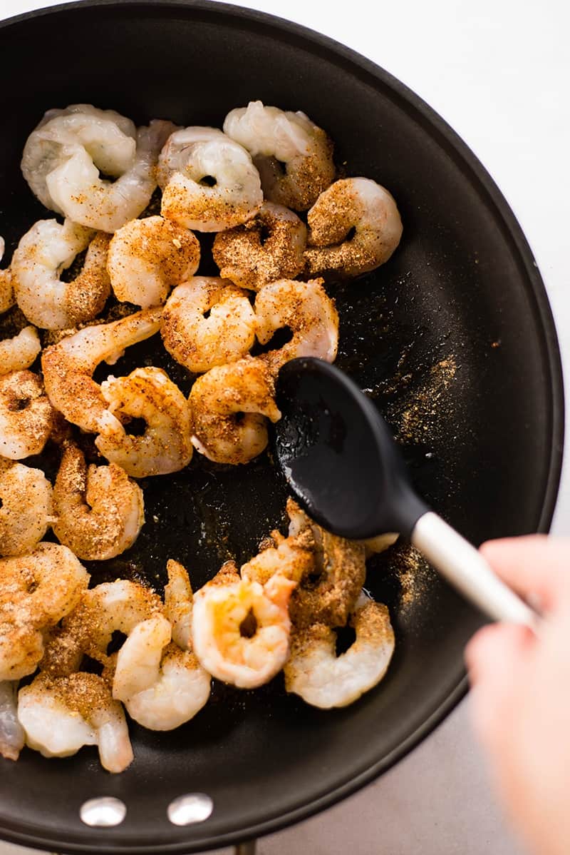 Peeled and seasoned shrimp, sautéing in a skillet to make spicy shrimp tacos recipe
