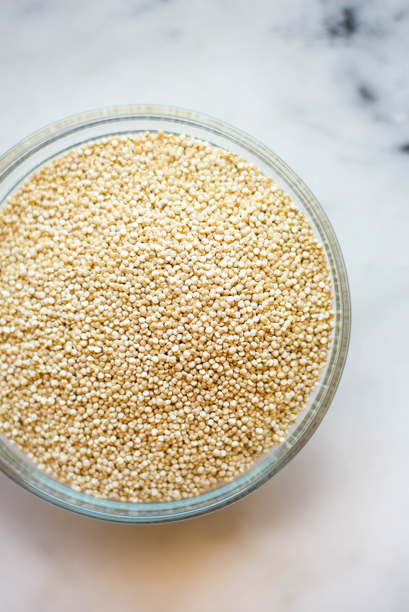 Overhead view of a glass bowl filled with uncooked quinoa for the Quinoa Taco Bowl.