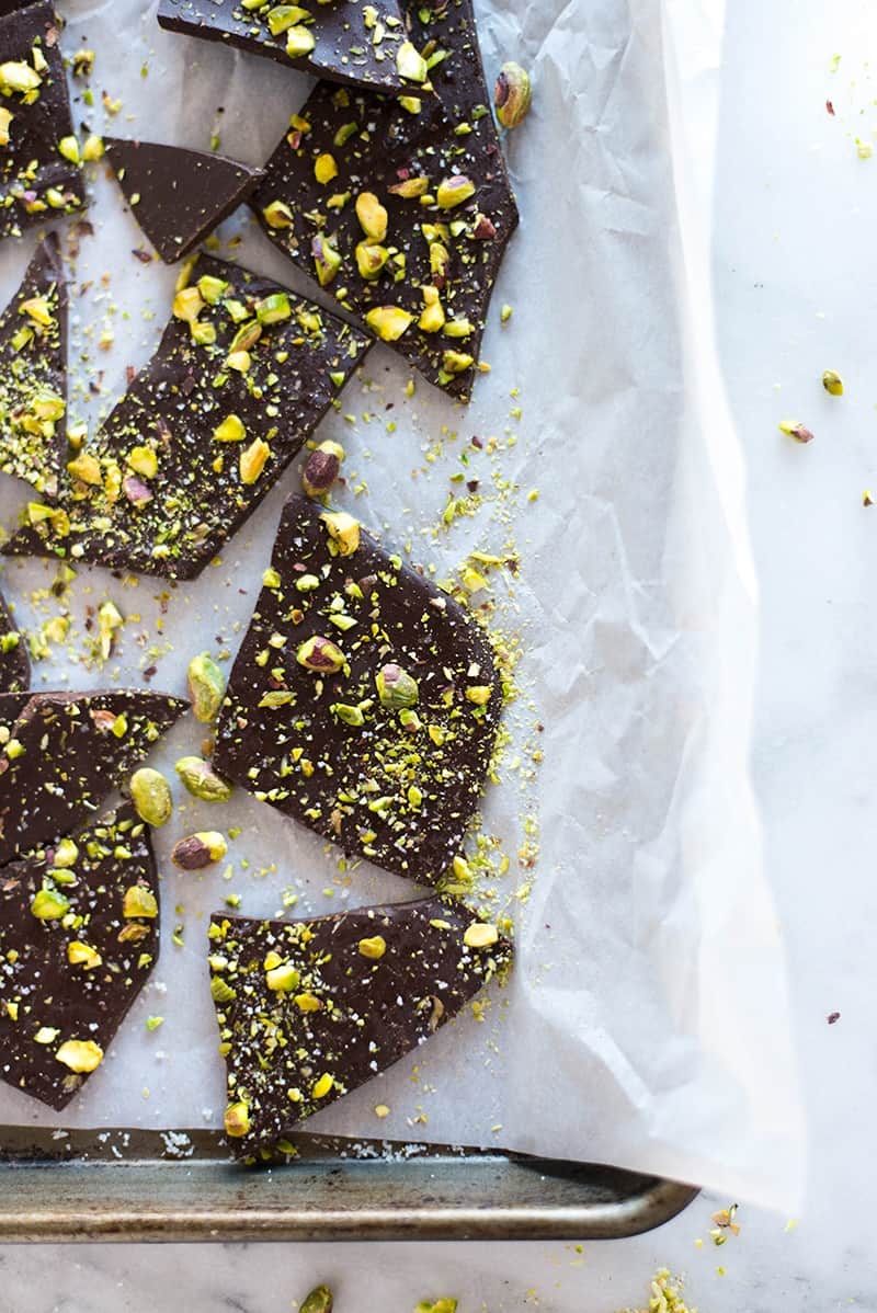 Overhead image of 3 Ingredient Pistachio Dark Chocolate Bark broken into pieces on a parchment paper lined baking sheet.