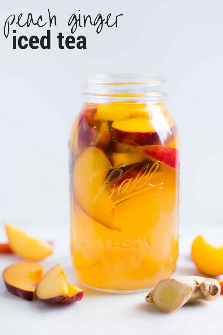 Quart size mason jar with peach slices and fresh ginger, ready to drink.