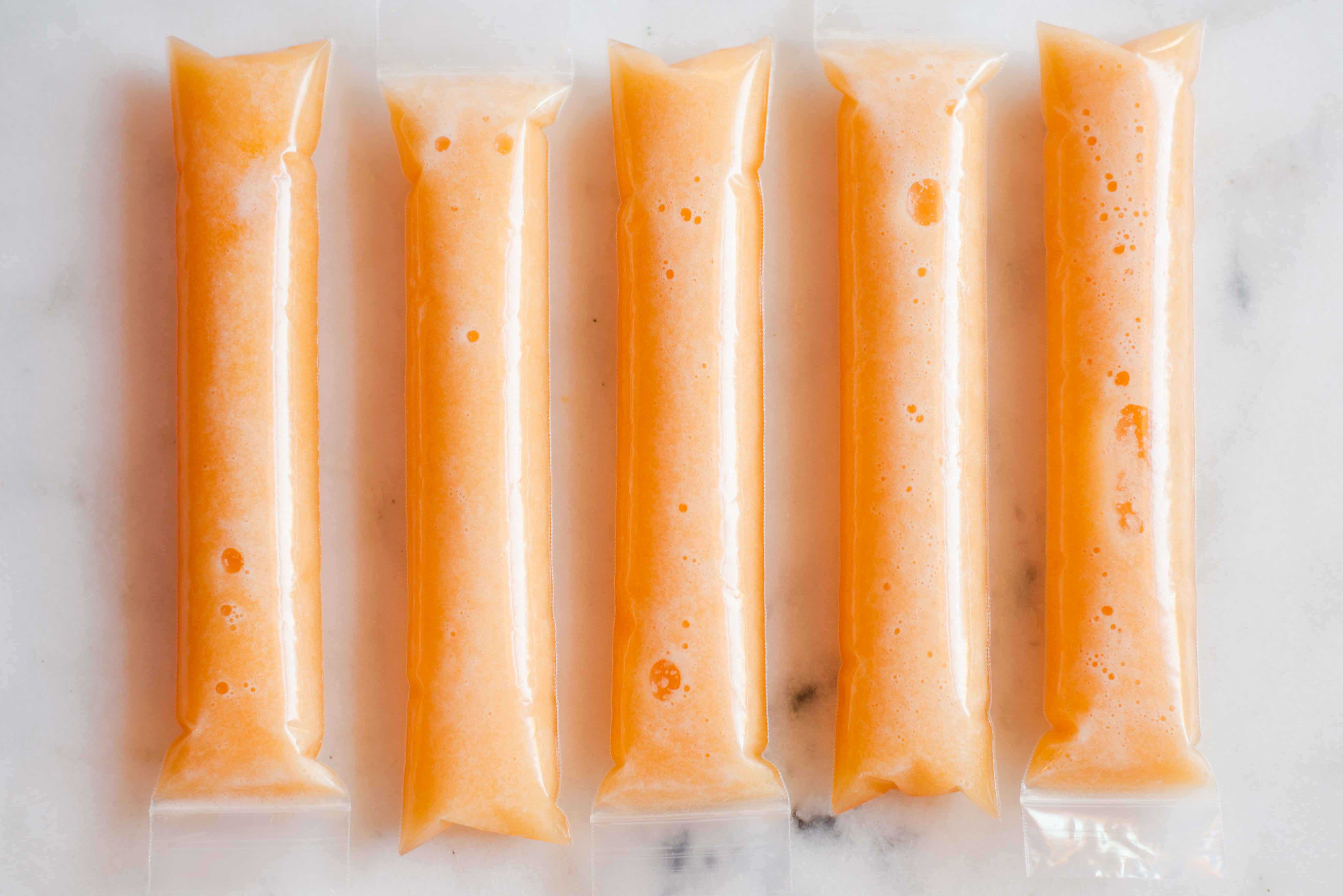 Pureed sugar kiss melons in ice pop wrappers, ready to be placed into the freezer.