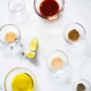 Ingredients separated for chipotle chicken marinade, including adobo sauce, cumin, onion powder, garlic powder, sea salt, pepper, lime juice, and olive oil.