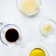Ingredients separated for honey garlic chicken marinade, including garlic, raw honey, low sodium soy sauce, and olive oil.