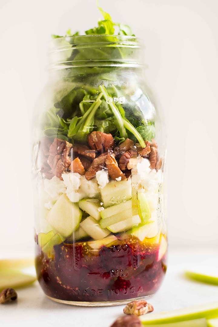 Quart size mason jar filled with beet and goat cheese salad, which includes a white wine vinegar dressing, granny smith apples, beets, crumbled goat cheese, toasted pecans, and baby arugula.