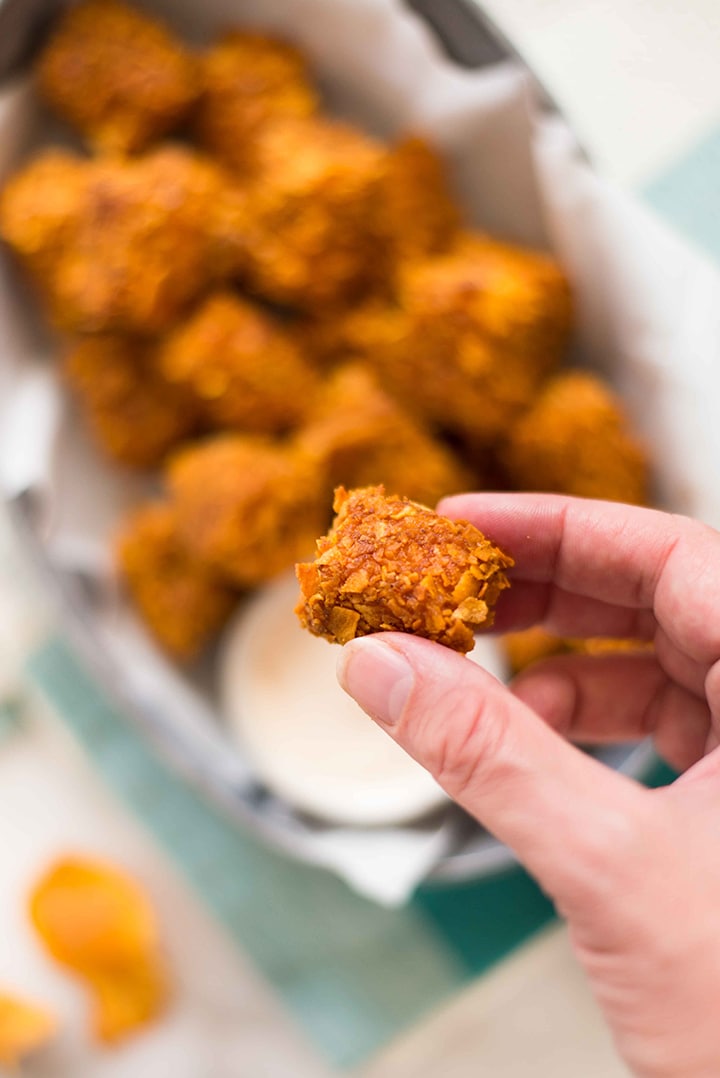 Hand holding one baked sweet potato tot, ready to dip into the greek yogurt dip and eat.