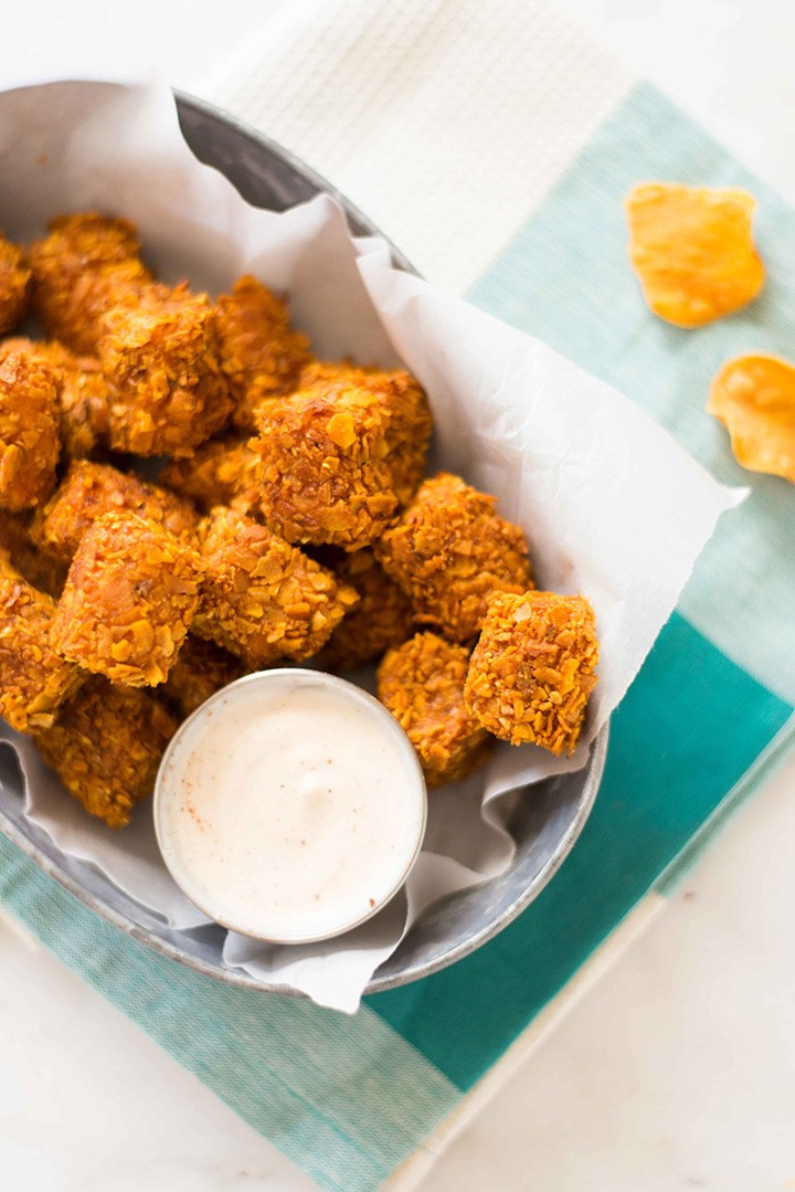 Overhead close up view of a white bowl containing Crispy Baked Sweet Potato Tots with a small bowl of Greek Yogurt Dip.