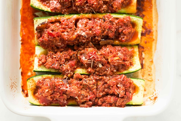 Close up shot of the cooked turkey and quinoa stuffed zucchini boats that are barked and ready to eat, still in the casserole dish.