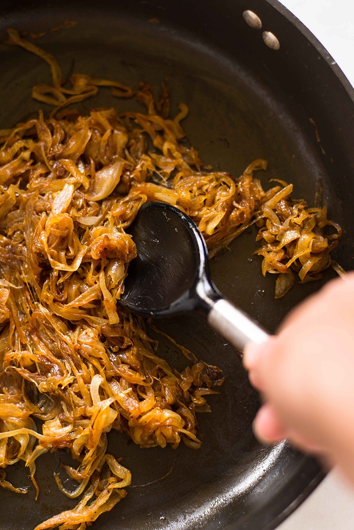 Large skillet with caramelized onions to show how to make caramelized onions for caramelized onion dip. 