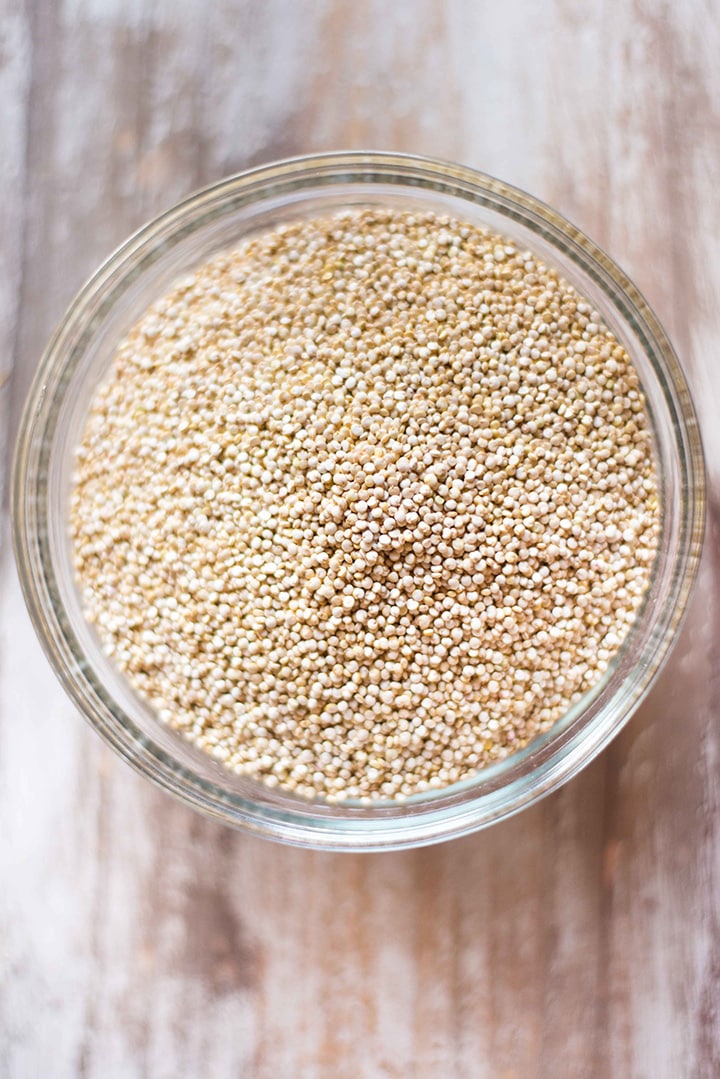 Overhead image of a glass bowl of organic quinoa which is uncooked/raw and will be cooked as a source of vegan protein.
