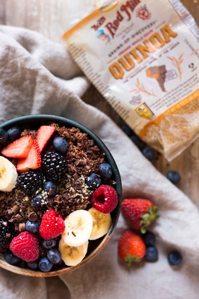 Close up overhead image of chocolate quinoa breakfast bowl containing strawberries, raspberries and blueberries.