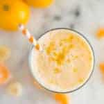 A glass of Orange Dreamsicle Smoothie with mandarin oranges, a banana, greek yogurt, vanilla extract, raw honey and almond milk topped with orange zest.
